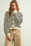 Woman wearing a black and white striped cardigan with beige pants on a light background