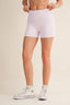 Person wearing white checkered shorts and white sneakers on a beige background