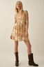 Woman wearing a floral dress and brown boots on a plain background