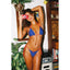 Woman in a blue and red bikini taking a selfie with a vintage camera in a room with plants and furniture.