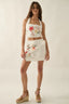 Woman wearing a floral embroidered top and skirt on a plain background