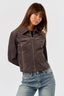 Woman wearing a brown western stitch design jacket and blue jeans against a white background