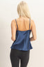 Woman wearing a blue satin camisole against a beige background
