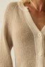 Close-up of a beige knitted cardigan with buttons on a neutral background