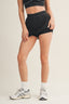 Person wearing black athletic shorts and a sports bra on a beige background