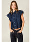 Woman wearing a sleeveless denim shirt and dark jeans against a plain background
