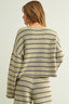 Woman wearing a striped sweater and pants on a plain background
