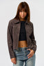 Woman wearing a brown western stitch design jacket and blue jeans against a white background