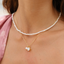 Pearl necklace with a gold chain and star-shaped pendant on a person wearing a pink top.