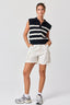 Person wearing a black and white striped sleeveless top with white shorts on a white background