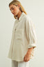 Woman wearing a beige oversized shirt against a white background