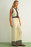 Woman wearing a sleeveless top and long skirt with a white background