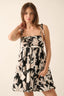 Woman wearing a black and white floral dress against a plain background
