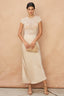 Woman wearing a beige dress with lace top against a beige background