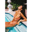 Woman in a colorful bikini lying by a pool with decorative elements in the background