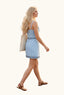 Woman in a light blue dress walking past a 'Game Day Gear' stand at an outdoor event.