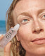 Person applying OSEA ocean eyes product to their face with a beach background
