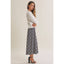 A woman modeling a white long-sleeve knit top and a navy and white plaid midi skirt, paired with black ankle-strap heels, against a plain beige studio background.