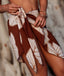 Brown floral patterned sarong being held by a person against a blurred natural background
