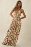 Woman wearing a long, patterned dress against a plain background