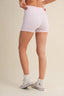 Person wearing white checkered shorts and white sneakers on a beige background