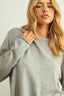 Woman wearing a gray sweater against a plain background