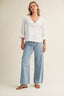 Woman wearing a white blouse and light blue jeans on a plain background
