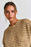 Woman wearing a beige knitted sweater against a plain background
