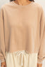 Beige long-sleeve top worn by a person on a plain background
