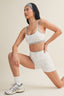Woman wearing a sports bra and shorts on a beige background