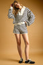 Woman wearing a black and white striped sweater and shorts set on a beige background
