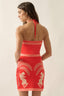 Woman wearing a red dress with white patterns on a beige background