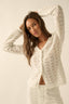 Woman wearing a white pointelle crochet outfit against a plain background