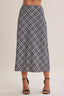 A model wearing a navy and white plaid midi skirt with black strappy high-heeled sandals, shown from the waist down against a plain light beige background.