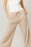 Person wearing beige striped pants and a white top on a plain background