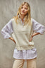 Woman wearing a light-colored sweater vest over a white shirt with a neutral background