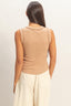 Woman wearing a beige sleeveless top and light-colored pants against a plain background