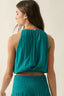 Woman wearing a teal sleeveless top and skirt against a beige background