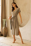 Woman wearing a gray wrap dress in a room with a large mirror and decorative vase.