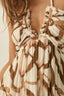 Brown and white patterned dress with ruffled straps on a neutral background