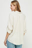Woman wearing a cream-colored blouse with rolled-up sleeves on a white background