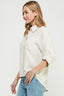 Woman wearing a light-colored shirt and blue jeans on a white background