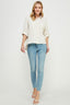 Woman wearing a light-colored shirt and blue jeans on a white background