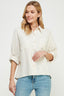 Woman wearing a light-colored shirt and blue jeans on a plain background