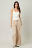 Woman wearing a white top and beige striped pants on a plain background