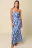 Woman wearing a blue strapless dress with white floral pattern on a beige background