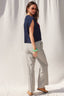 Woman wearing a navy top and striped pants against a white curtain background