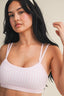 Woman wearing a light pink checkered top against a neutral background