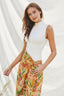 Woman wearing a white sleeveless top and colorful floral skirt against a white background