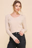 Woman wearing a beige cable knit sweater and black jeans on a beige background